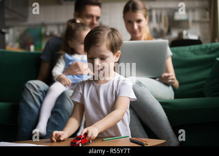 Little boy playing with toy cars while parents sitting together Stock Photo