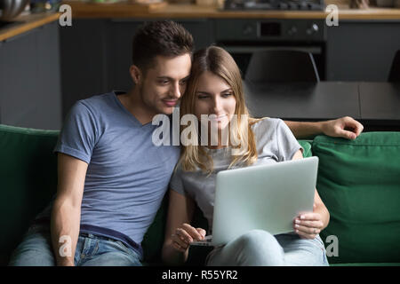 Happy man and woman sitting together and using laptop Stock Photo