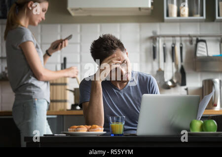 Young couple using laptop and smartphone in the kitchen Stock Photo