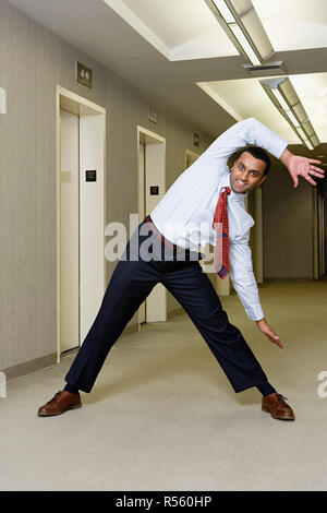 Office worker stretching in corridor Stock Photo