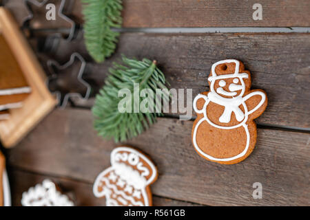 Cookies in the form of snowman Christmas winter morning. Woman draws Icing on honey gingerbread cookies. Wooden brown table. copy space. Stock Photo