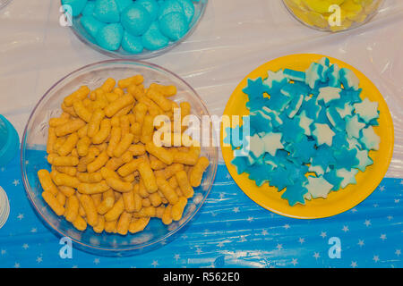 Top view of bowls with colorful sweet tasty gummy candy and bamba snack at children birthday party Stock Photo
