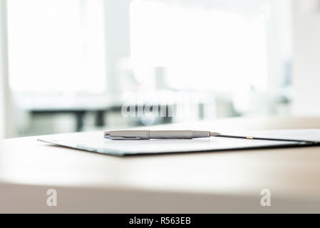 Low angle view of ink pen lying on document or contract on office desk. Stock Photo