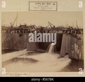 Ceremony of admitting water to Victoria Dock by Lady Reay [Victoria Dock construction, Bombay]. A general view of water pouring into the Victoria Dock, with dignitaries and guests gathered along the top of the entrance to the dam. Bombay Port Trust. Prince's Dock Extension Works. 21 Feb. 1888. Photograph. Source: Photo 173/(64). Language: English. Stock Photo