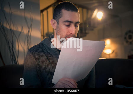 Man reading papers while sitting on a sofa in the room Stock Photo