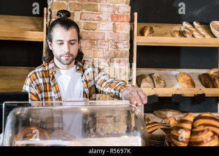 handsome adult seller working at bakery