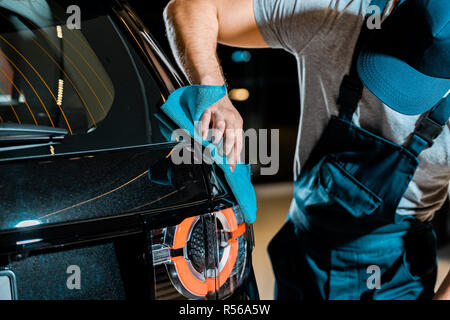 partial view of auto mechanic cleaning car with rag at auto repair shop Stock Photo