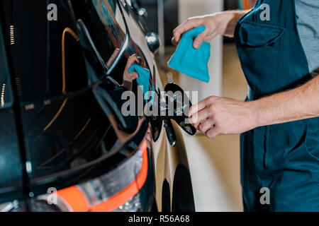 partial view of auto mechanic with rag checking car at auto repair shop Stock Photo
