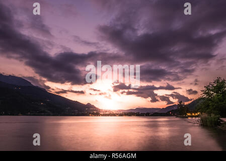 Dramatic sunset cloudscape over mountain lake, warm Stock Photo