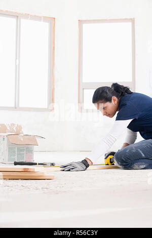 A female builder measuring a plank of wood Stock Photo