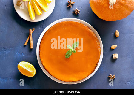 Tasty pumpkin and orange pie on blue stone background. Traditional autumn dish. Healthy vegetarian food. Top view, flat lay Stock Photo
