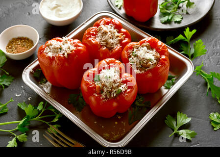 Stuffed red peppers with minced meat, rice, onion, parmesan cheese on black stone table. Stock Photo