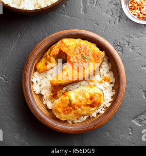 Delicious fish curry with rice in wooden bowl on black stone table. Indian style food. Top view, flat lay Stock Photo