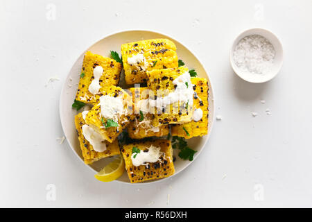 Grilled corn on cob with sauce and grated parmesan. Tasty vegetarian food. Top view Stock Photo