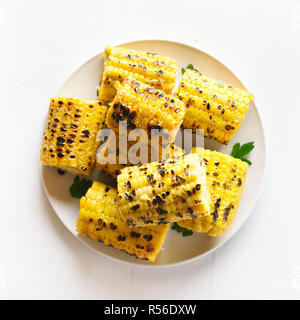 Grilled corn cobs on plate over white stone background. Tasty vegetarian food. Top view Stock Photo
