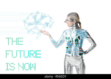 silver cyborg holding digital data isolated on white with 'the future is now' lettering, future technology concept Stock Photo