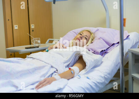 Bedridden female patient recovering after surgery in hospital care. Stock Photo