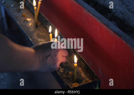 Buddhists make merit,Placing a lighted candle and lit incense with candles frame on the altar of Buddha  at temple.  Selective focus. Stock Photo