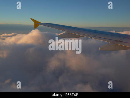 Plane flying above the white and fluffy clouds, view from airplane porthole. Spain Stock Photo