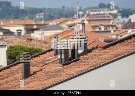 Old clay chimney pots and brick chimney stacks on old tiled roof complete with TV aerials in England, Stock Photo