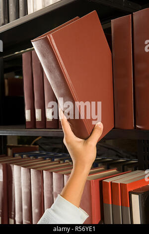 Female student reaching for a book Stock Photo