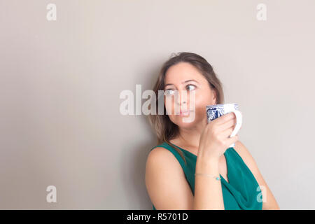Young woman is looking sideway drinking coffee Stock Photo
