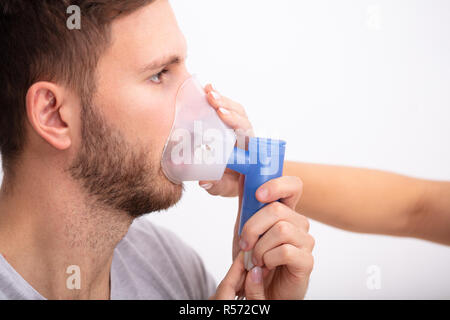 Side View Of Young Female Doctor Holding Oxygen Mask Over Male Patient's Mouth Stock Photo