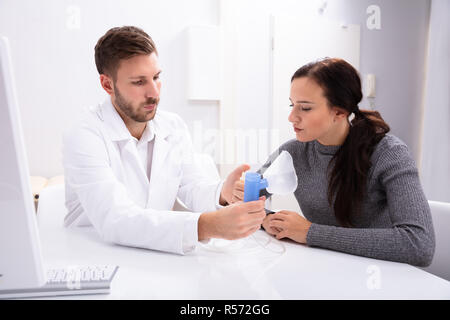 Young Male Doctor Giving Information On Using Oxygen Mask To Woman In Clinic Stock Photo