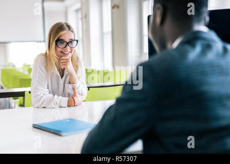 Couple of young colleagues working in modern office. Cheerful man hr interviewing female candidate. Stock Photo