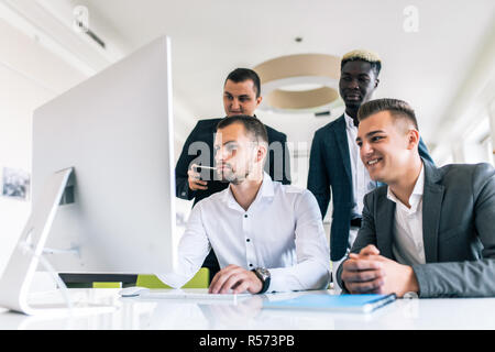 Concentrated business team discussing presentation together in office. Serious young multiethnic business expert preparing report and discussing strat Stock Photo
