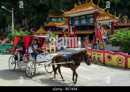 Ipoh, Malaysia - Apr 15, 2018: Unidentified visitors on horse coach passing by the entrance of Ling Sen Tong, Temple cave, Ipoh, Malaysia - Ling Sen T Stock Photo