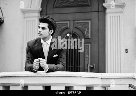 Elegant indian macho man model on suit and pink tie leaned on the railing. Stock Photo
