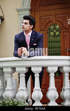 Elegant indian macho man model on suit and pink tie leaned on the railing. Stock Photo