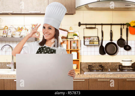 Happy asian female chef with ok gesture holding white board Stock Photo
