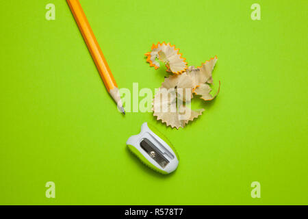 Sharpened pencil and sharpener on green background Stock Photo