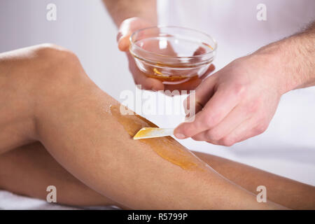 Beautician Waxing A Woman's Leg Stock Photo