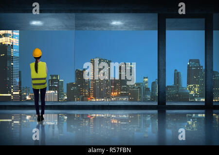 Young asian engineer woman standing seeing through window glass Stock Photo