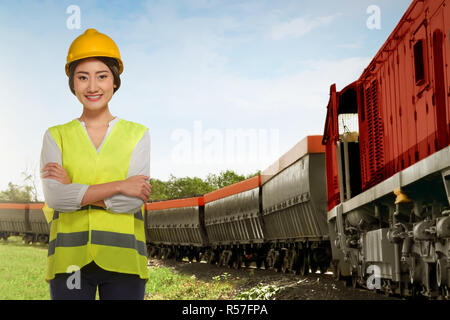 Beautiful asian railway employee woman standing beside freight train Stock Photo