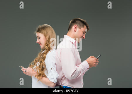 Business concept. The two young colleagues holding mobile phones on gray background Stock Photo