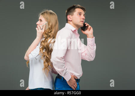 Business concept. The two young colleagues holding mobile phones on gray background Stock Photo