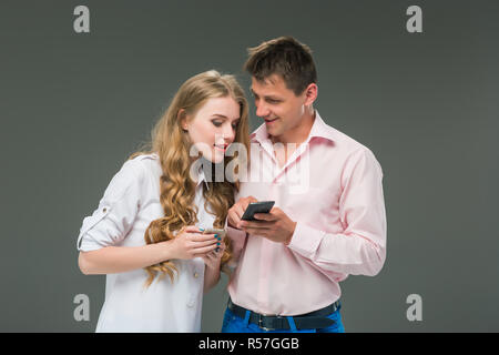 Business concept. The two young colleagues holding mobile phones on gray background Stock Photo