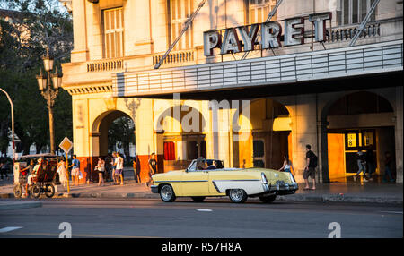 Classic 1950's yellow and white  convertible by the Payret Movie Theater along with tourists. Stock Photo