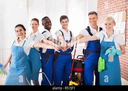 Smiling Diverse Janitors Stacking Hands Stock Photo