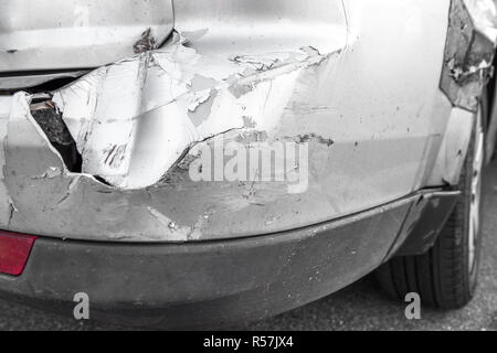 Silver car with rear part damaged in crash accident or collision with scratched paint and dented rear bumper metal body. Stock Photo