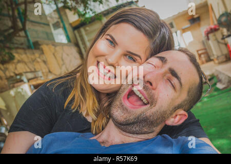 Young couple enjoying together in the backyard. They are smiling, laughing and making funny faces together Stock Photo