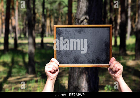 Human hands holding an empty wooden frame with a black background Stock Photo