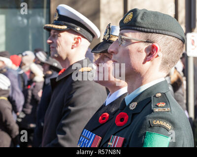 OTTAWA, CANADA - NOVEMBER 11, 2018: Soldiers from Canadian Army, two men, a woman, from Navy & ground forces, wearing remembrance poppy, standing on c Stock Photo