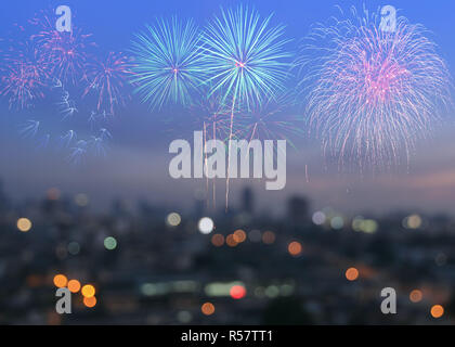 Colorful fireworks on blur city skyline background at twilight Stock Photo