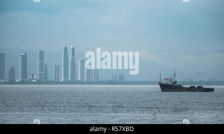 Large tug boat near the Panama Canal sits anchored and idle in hot humid weather.  Panama City in background.  Summer storm approaches. Stock Photo