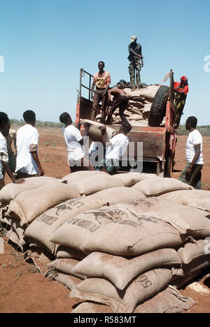 1993 - Men from the village of Maleel stack bags of wheat as a Marine Heavy Helicopter Squadron 363 (HMH-363) CH-53D Sea Stallion helicopter prepaers to drop another load during the multinational relief effort OPERATION RESTORE HOPE.